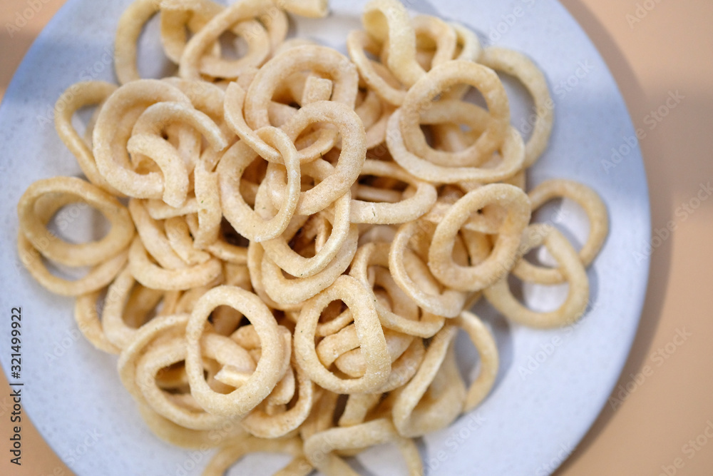 Beer snack dough rings view from above. Onion rings in breading. Salty crispy snacks on a plate. Beer snack dough rings view from above. Onion rings in breading. Salty crispy snacks on a plate.