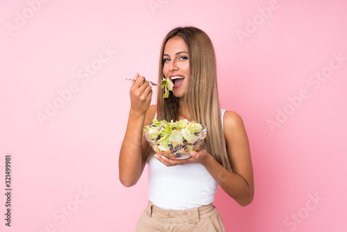 Young blonde woman with salad over isolated background