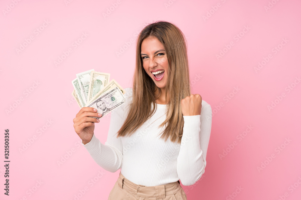 Young blonde woman over isolated pink background taking a lot of money Young blonde woman over isolated pink background taking a lot of money