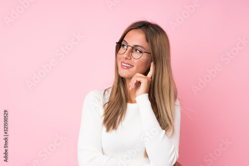 Young blonde woman over isolated pink background with glasses