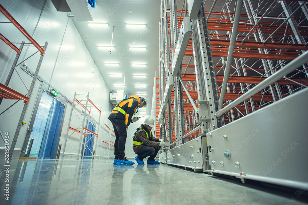 Obraz premium Two technician inspector check machine shelf in cold warehouse.