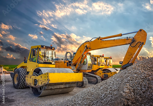 Parked drum roller and excavators at the construction site, after work