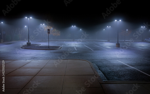 An Empty Parking Lot on a Cold, Rainy Night - with Vacant Parking Spaces and a Thick Mist Gathering Under the Lights