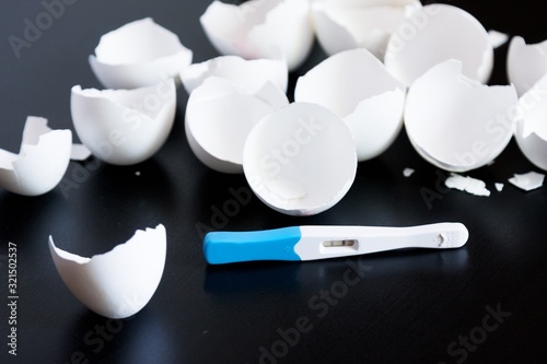 Infertility. Negative pregnancy test and eggshell on black background photo