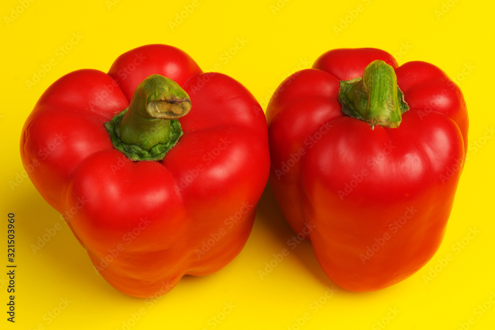 two red bell peppers on yellow background. close up two red bell peppers on yellow background. close up