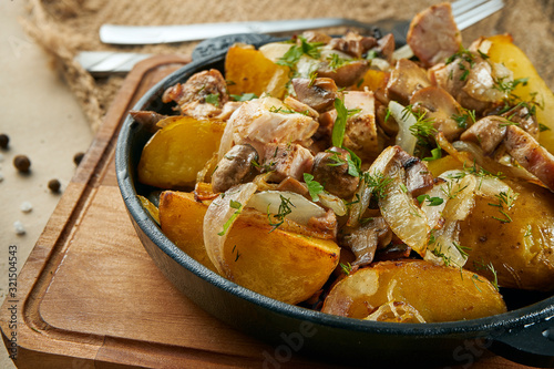 Dish in a pan - baked potatoes with onions, chicken and mushrooms on rustic background. Traditional Ukrainian dish. Close up view on food