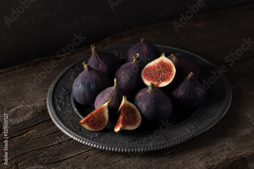 Fresh ripe figs. Breakfast with figs, cheese, honey and nuts. A few figs on an old wooden background. Whole figs and one fig sliced. Fresh fruits, purple figs on the wooden background. Autumn harvest.