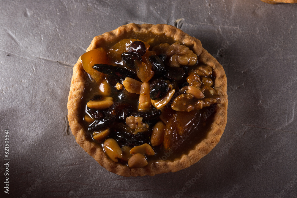 tart with salted caramel. Tart with nuts and caramel on a rustic background. Tartlets with dried fruits and nuts. Homemade tartlets with fruit and coffee. Dessert on a gray concrete table. Free space tart with salted caramel. Tart with nuts and caramel on a rustic background. Tartlets with dried fruits and nuts. Homemade tartlets with fruit and coffee. Dessert on a gray concrete table. Free space