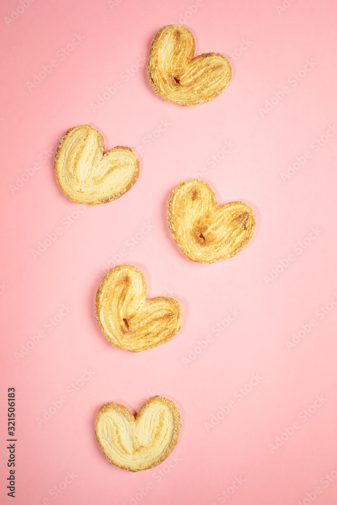 Trendy pink pastel background with five heart shape cookies. Holiday pastries for Valentine's day or Mother's day or Women's day. Top view, flat lay.