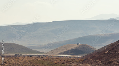 Two people and SUV car on a hilltop in the highlands