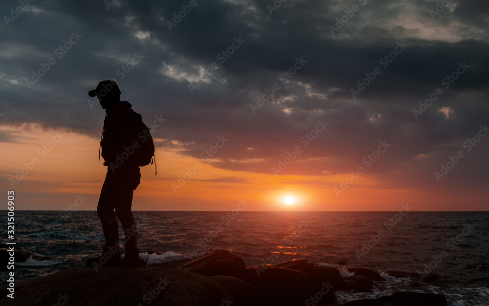 Silhouette of backpacker with warm and sunset low lighting.