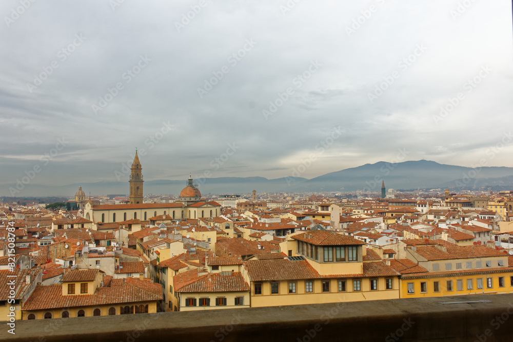 Florence Firenze view from a rooftop during winter season. Really cloudy sky and lovely red and oranges roofs of the old and historic buildings from Tuscany.