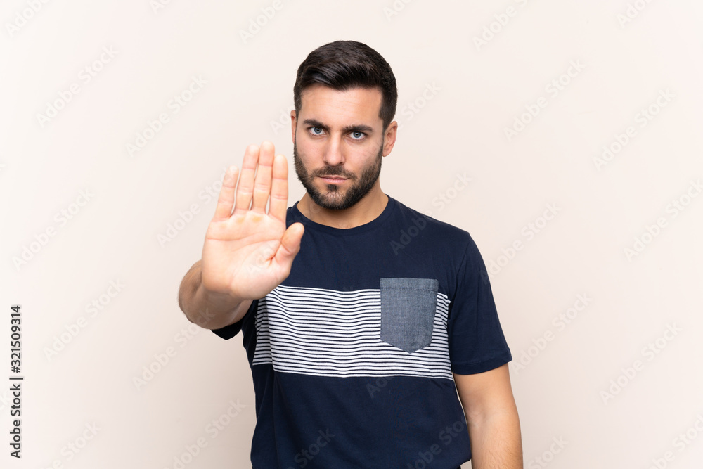 Young handsome man with beard over isolated background making stop gesture Young handsome man with beard over isolated background making stop gesture