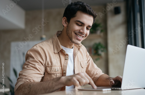 Happy asian student studying, learning language. Attractive business man working start up project in office. Portrait of successful Indian freelancer copywriter using laptop, typing on keyboard photo