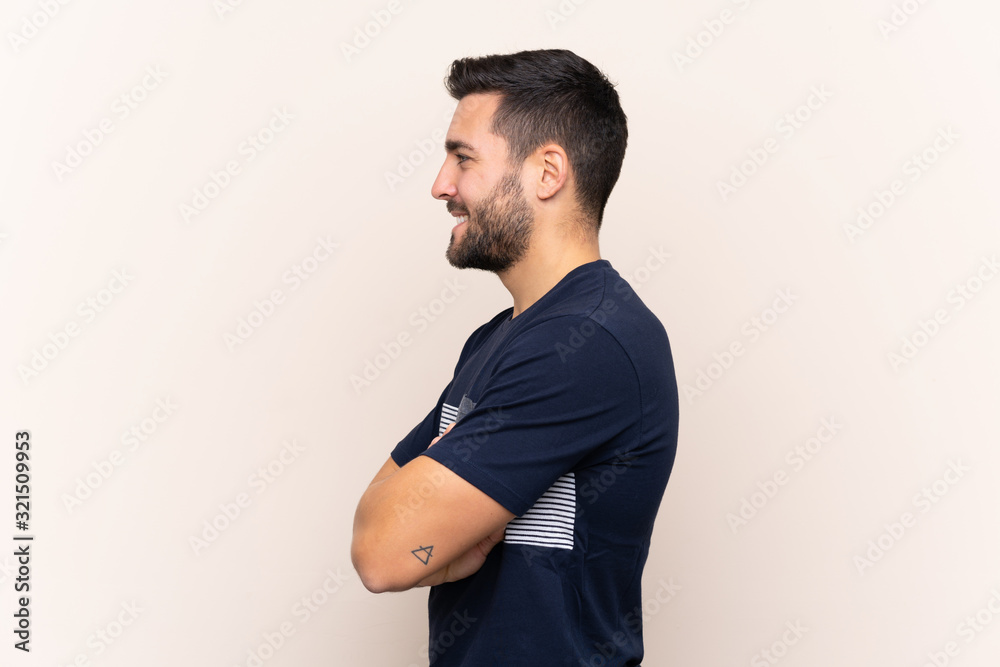 Young handsome man with beard over isolated background in lateral position