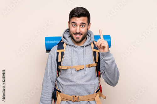 Young mountaineer man with a big backpack over isolated background pointing with the index finger a great idea photo