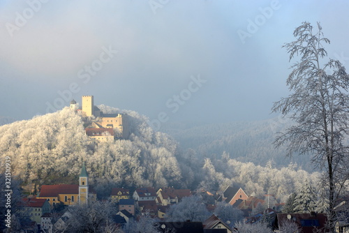 Winterzauber. Kleines Dorf mit Kirche am Fuß einer mittelalterlichen Burg im Raureif