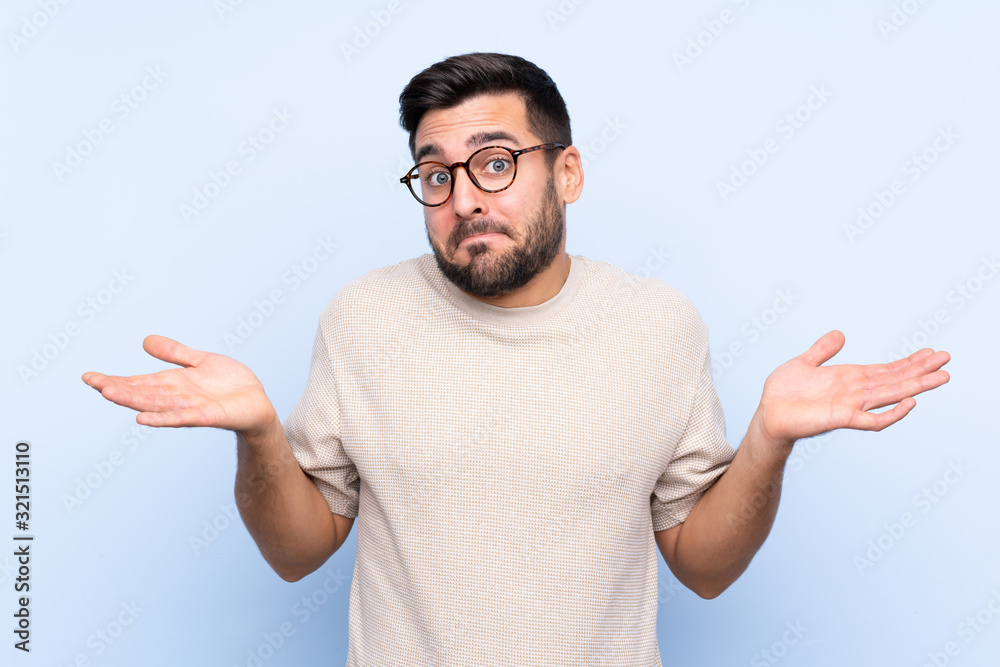 Young handsome man with beard over isolated blue background having doubts with confuse face expression Young handsome man with beard over isolated blue background having doubts with confuse face expression