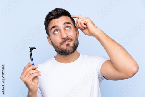 Young handsome man shaving his beard over isolated background having doubts and with confuse face expression