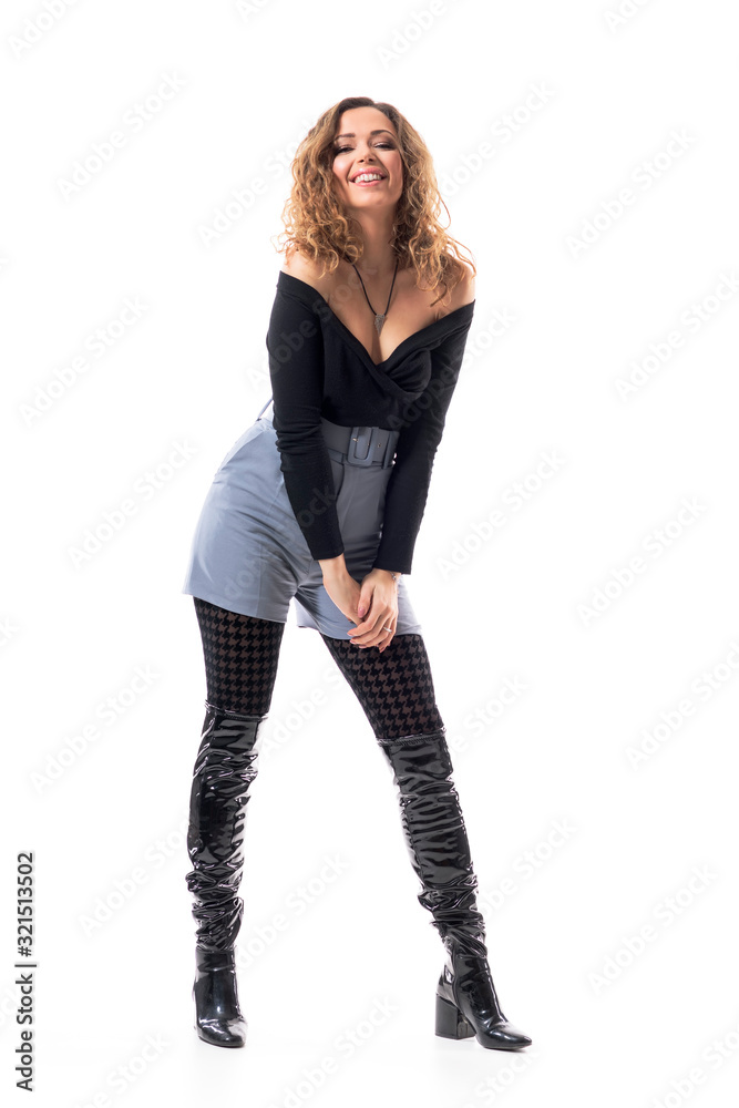 Cool modern fashionable young woman with curly hair posing in black leather knee-high boots. Full body length isolated on white background. Cool modern fashionable young woman with curly hair posing in black leather knee-high boots. Full body length isolated on white background.