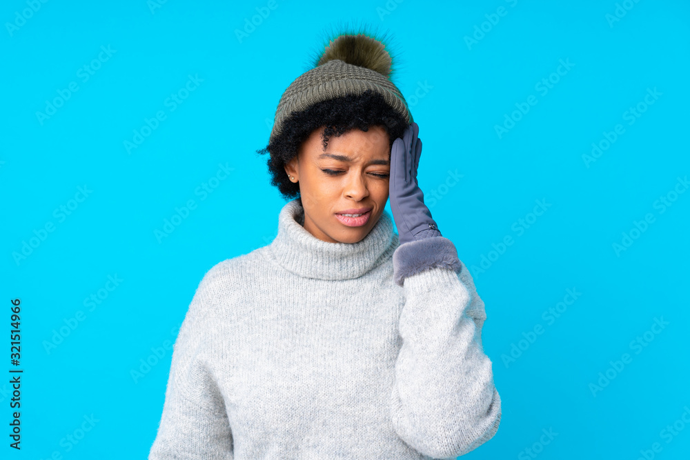 African american woman with winter hat over isolated blue background unhappy and frustrated with something. Negative facial expression