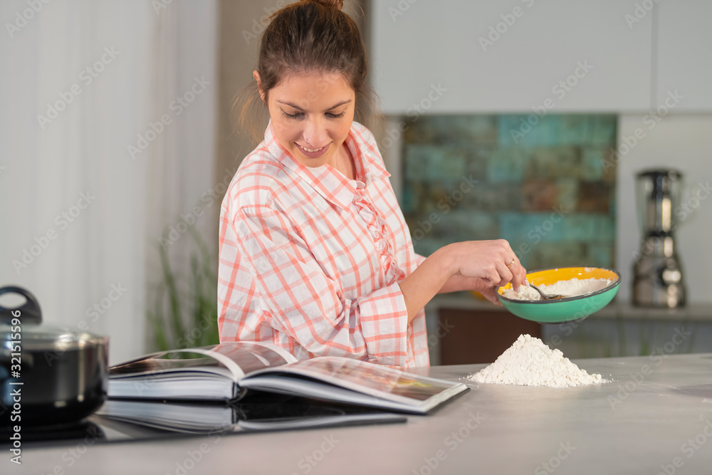 Woman holding a bowl and checking a cookbook Woman holding a bowl and checking a cookbook