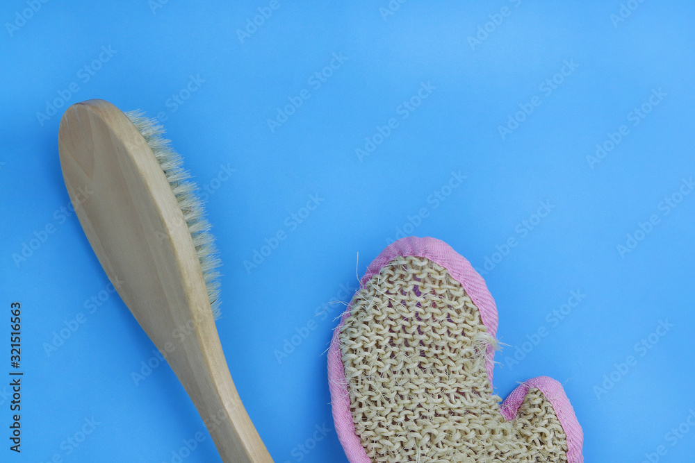 Anti-cellulite, wooden brush and glove with a hard surface for dry body massage on a blue background. Copy space - the concept of lymphatic drainage massage, skin elasticity, slim figure. Anti-cellulite, wooden brush and glove with a hard surface for dry body massage on a blue background. Copy space - the concept of lymphatic drainage massage, skin elasticity, slim figure.