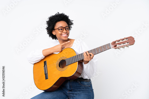 African american woman with guitar over isolated background pointing to the side to present a product