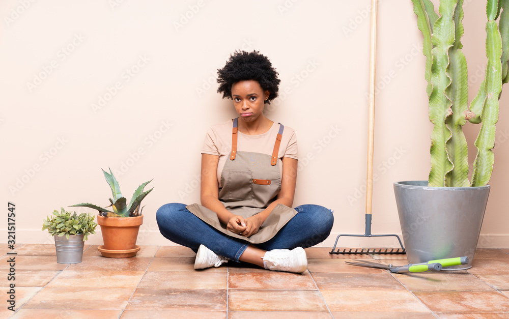 Gardener woman sitting on the floor with sad and depressed expression Gardener woman sitting on the floor with sad and depressed expression