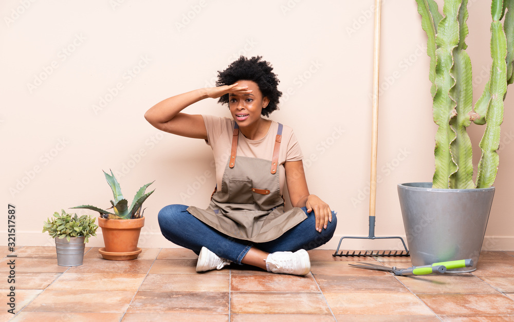 Gardener woman sitting on the floor looking far away with hand to look something Gardener woman sitting on the floor looking far away with hand to look something