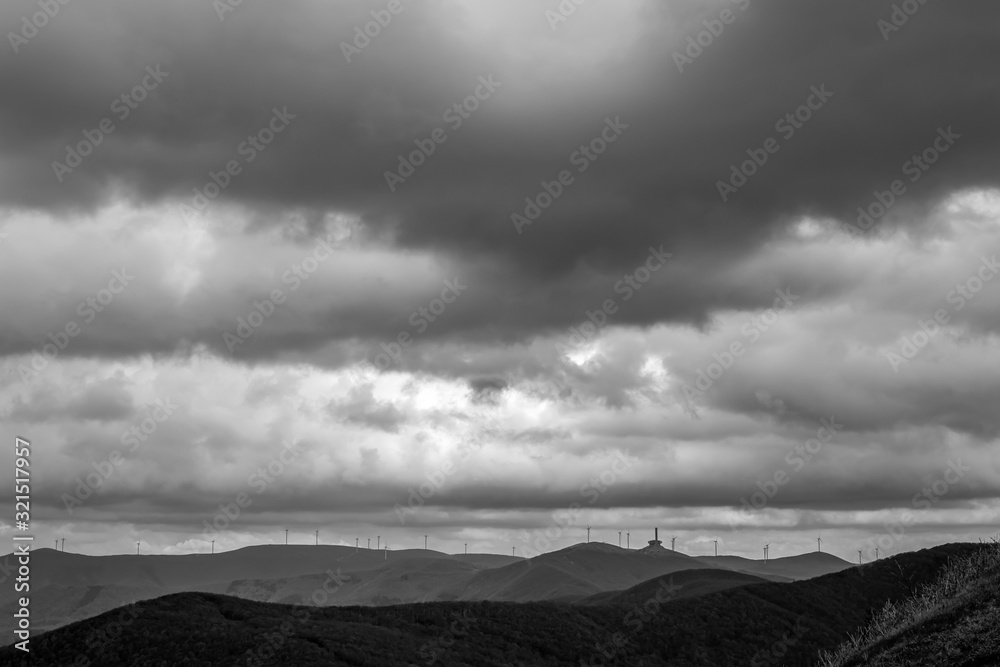 Dramatic autumn black and white view of the ruined Communist congress meeting building on Buzludzha peak, Stara Planina mountain in Central Bulgaria as seen from Shipka Memorial. Several wind turbines Dramatic autumn black and white view of the ruined Communist congress meeting building on Buzludzha peak, Stara Planina mountain in Central Bulgaria as seen from Shipka Memorial. Several wind turbines