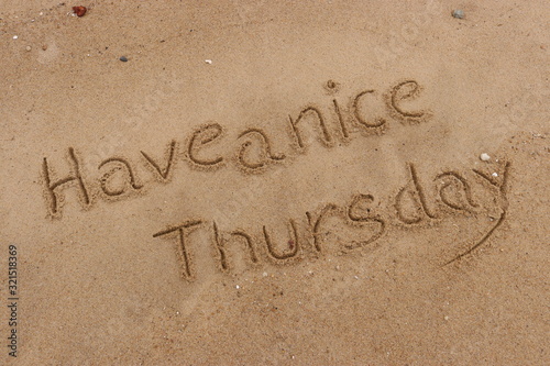 Handwriting words "Have a nice Thursday." on sand of beach.
