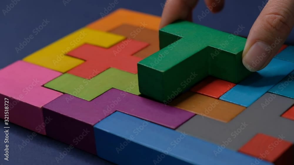 Closeup Slow motion. Hand holding piece of wooden block puzzle. wood cube stacking. Concept of complex and smart logical thinking. on a black background