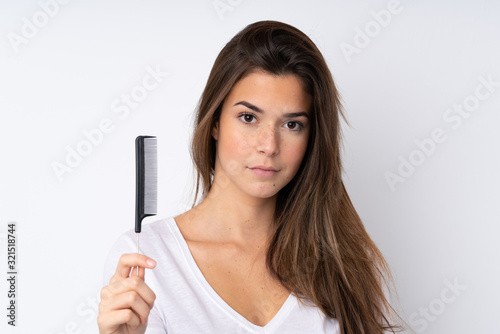 Teenager girl over isolated background with hair comb