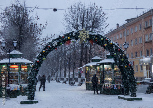 January 26,2020:Snowfall in the city. Christmas decorations .People are walking on the street in winter, under snowfall