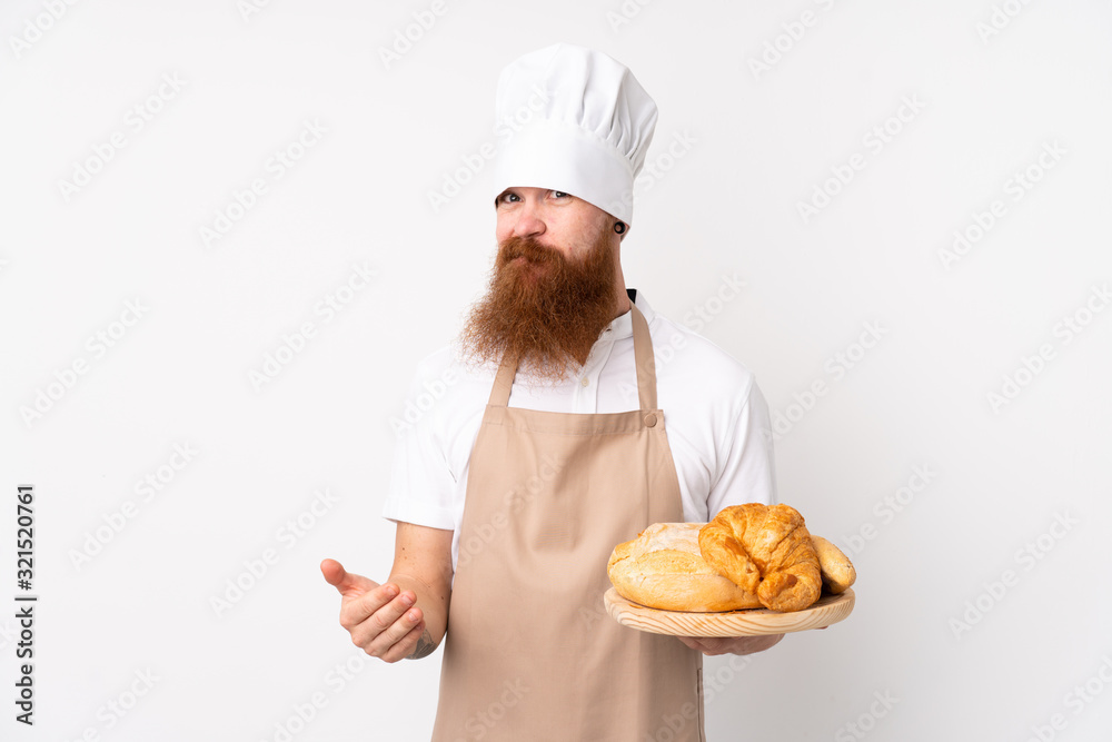 Redhead man in chef uniform. Male baker holding a table with several breads making doubts gesture while lifting the shoulders Redhead man in chef uniform. Male baker holding a table with several breads making doubts gesture while lifting the shoulders