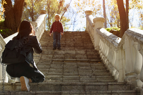 Boy descends stairs to his mother. Walk with baby in park. Naughty child.