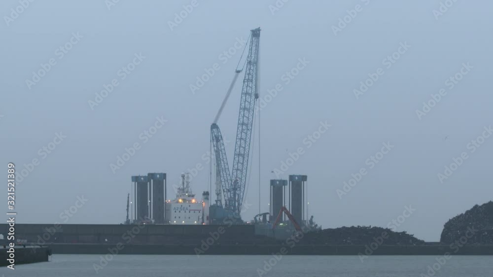 still medium shot of crane in shipyard located next to hills of rubbish still medium shot of crane in shipyard located next to hills of rubbish