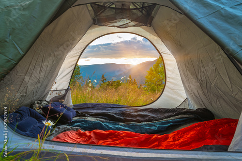 View from the tourist tent on the mountains, meadow, flowers, early in the morning when the sun rises. tourist tent