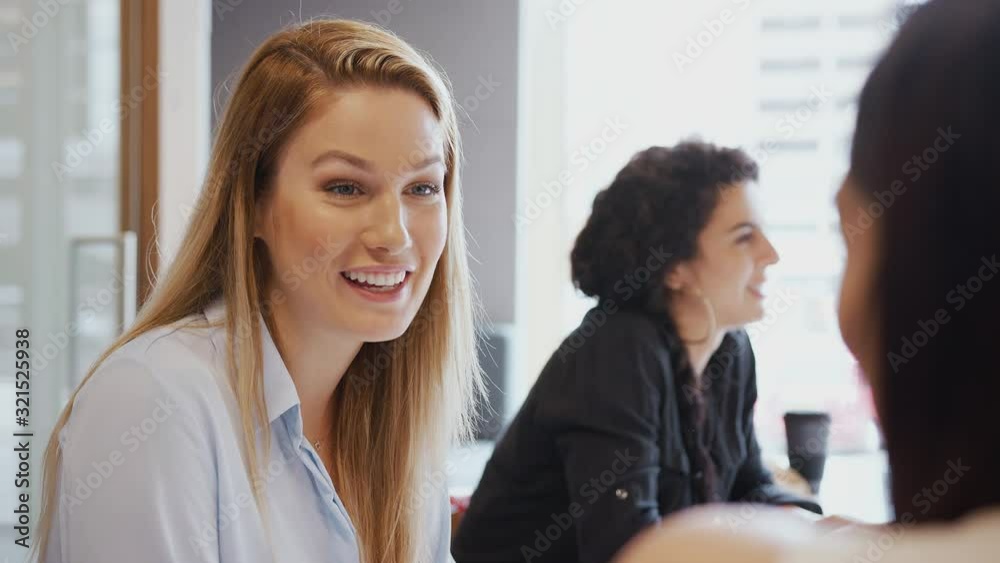 Young Businesswomen Meeting Around Table Having Discussion In Modern Workspace Young Businesswomen Meeting Around Table Having Discussion In Modern Workspace