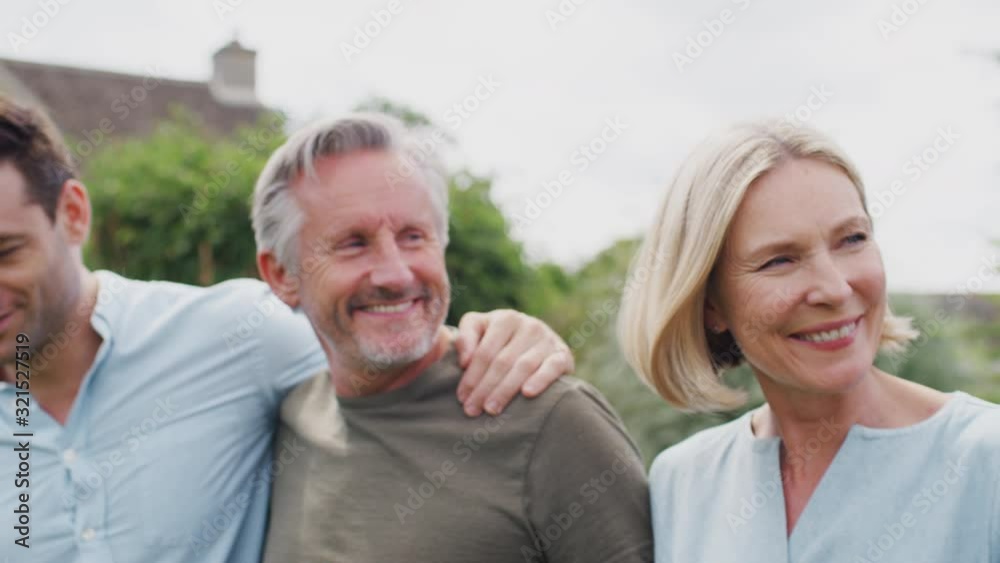 Family With Senior Parents And Adult Offspring Walking And Talking In Garden Together Family With Senior Parents And Adult Offspring Walking And Talking In Garden Together