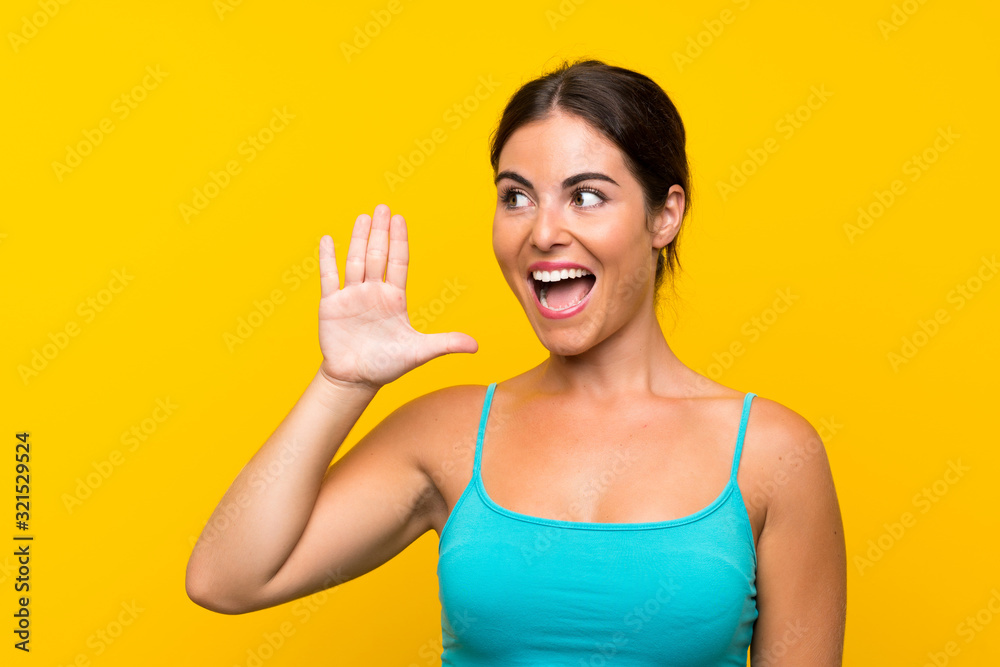 Young woman over isolated yellow background shouting with mouth wide open Young woman over isolated yellow background shouting with mouth wide open
