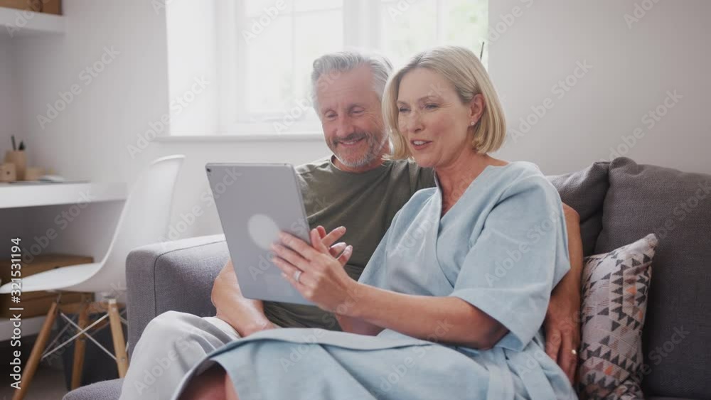 Senior Couple Sitting On Sofa At Home Making Video Call Using Digital Tablet Together Senior Couple Sitting On Sofa At Home Making Video Call Using Digital Tablet Together