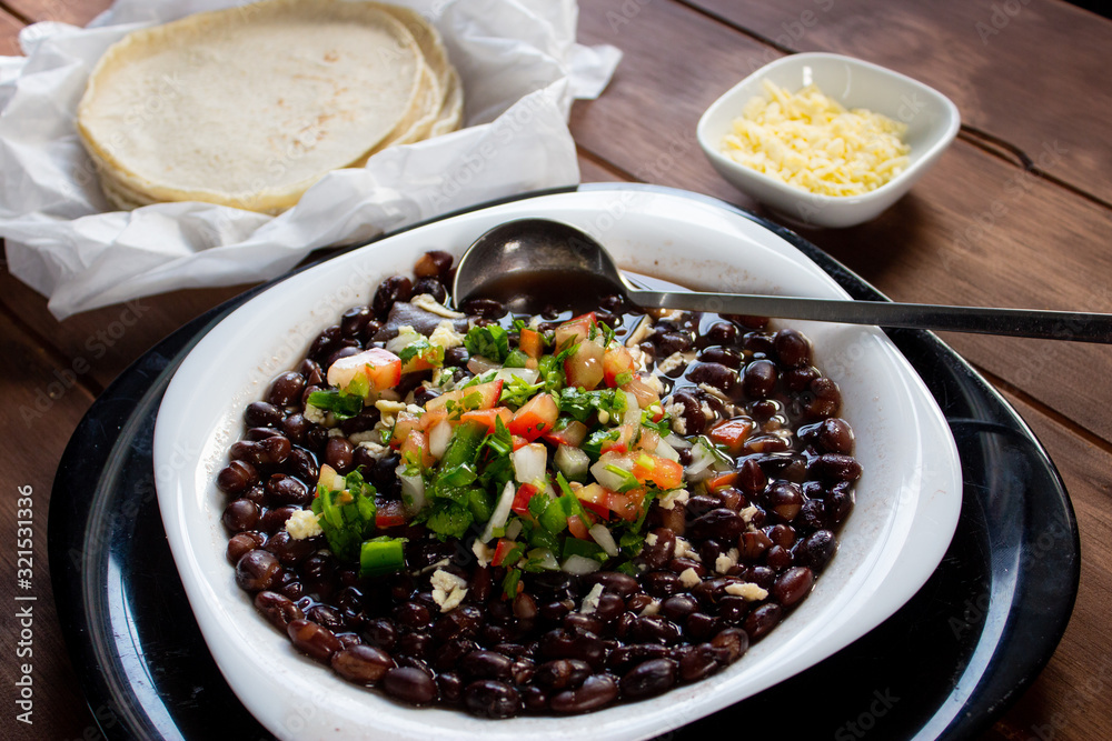 Plato de frijoles cocidos con tortillas y salsa mexicana quesillo en