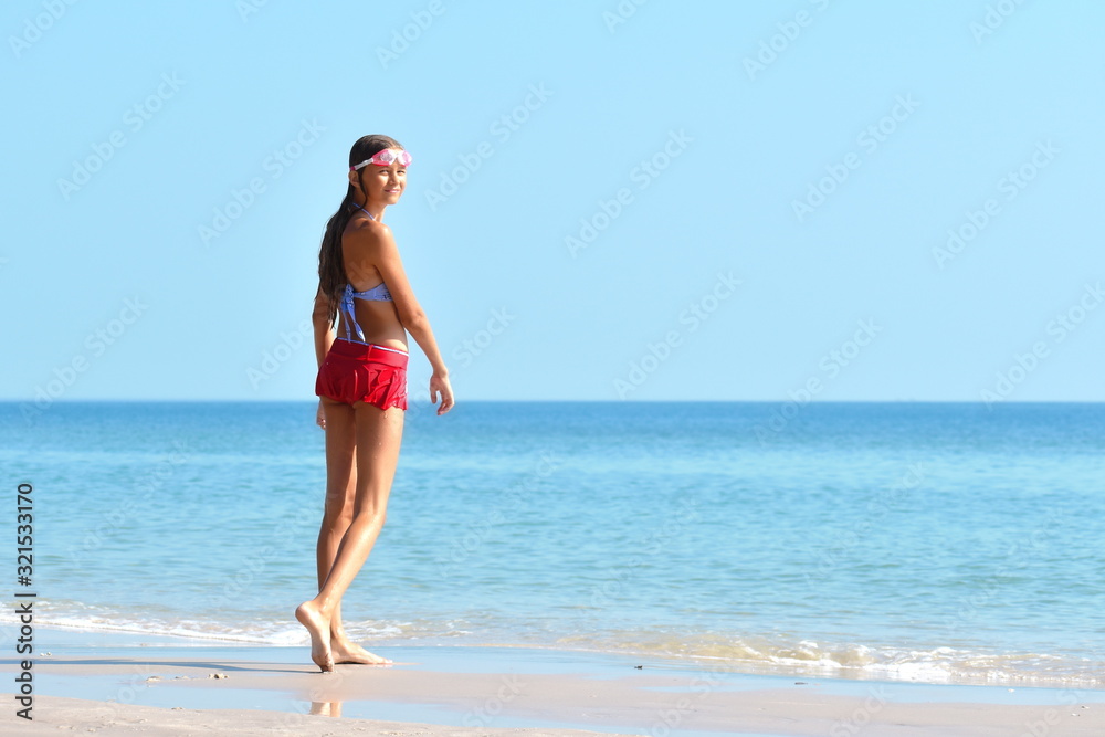 model teenager on the beach. a tropical Paradise for children. Girl in swimsuit at sea. Summer vacation in the tropics.