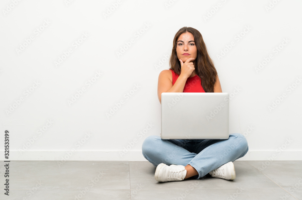 Young woman with a laptop sitting on the floor laughing Young woman with a laptop sitting on the floor laughing