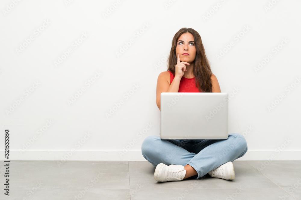 Young woman with a laptop sitting on the floor thinking an idea Young woman with a laptop sitting on the floor thinking an idea