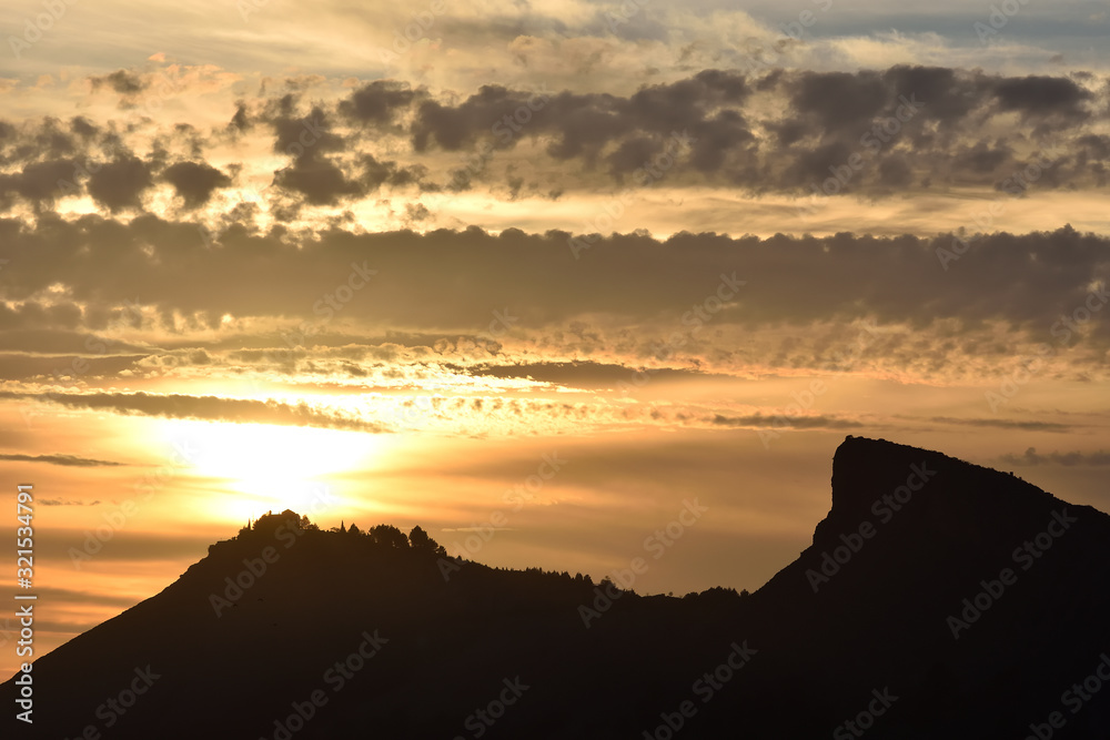 Mountain silhouette with house and trees on top on an amazing winter sunset in Granada