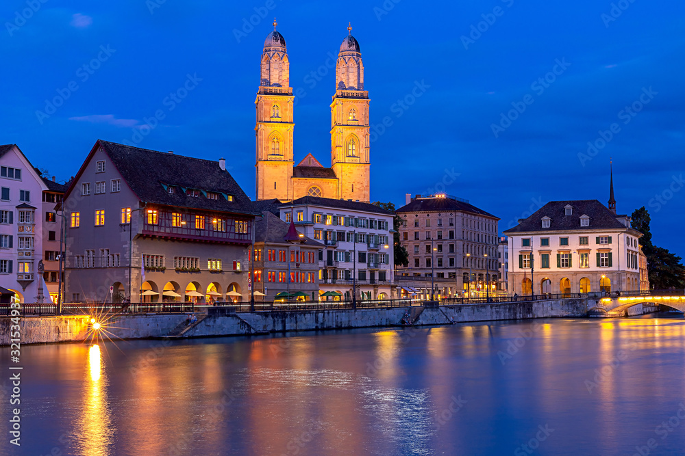 Zurich. View of the city embankment and the church Grossmunster at sunset.