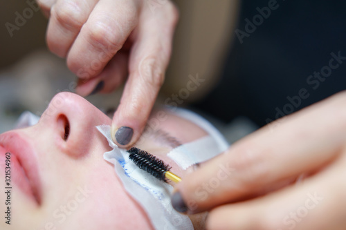 Close up on the hands of the beautician Eyelash Extension Procedure Woman Eye making artificial Long Eyelashes in a beauty salon